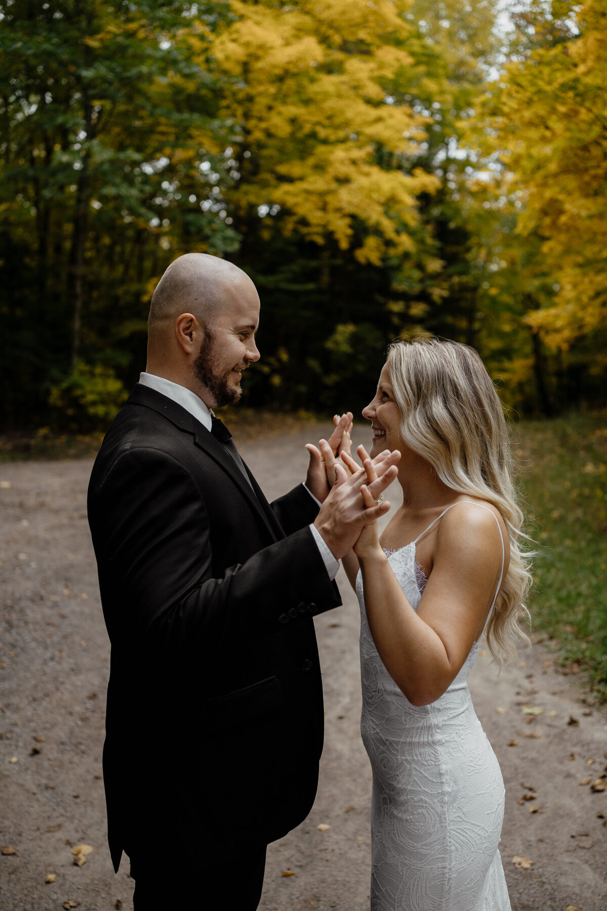bride and groom holding hands on trail in woods