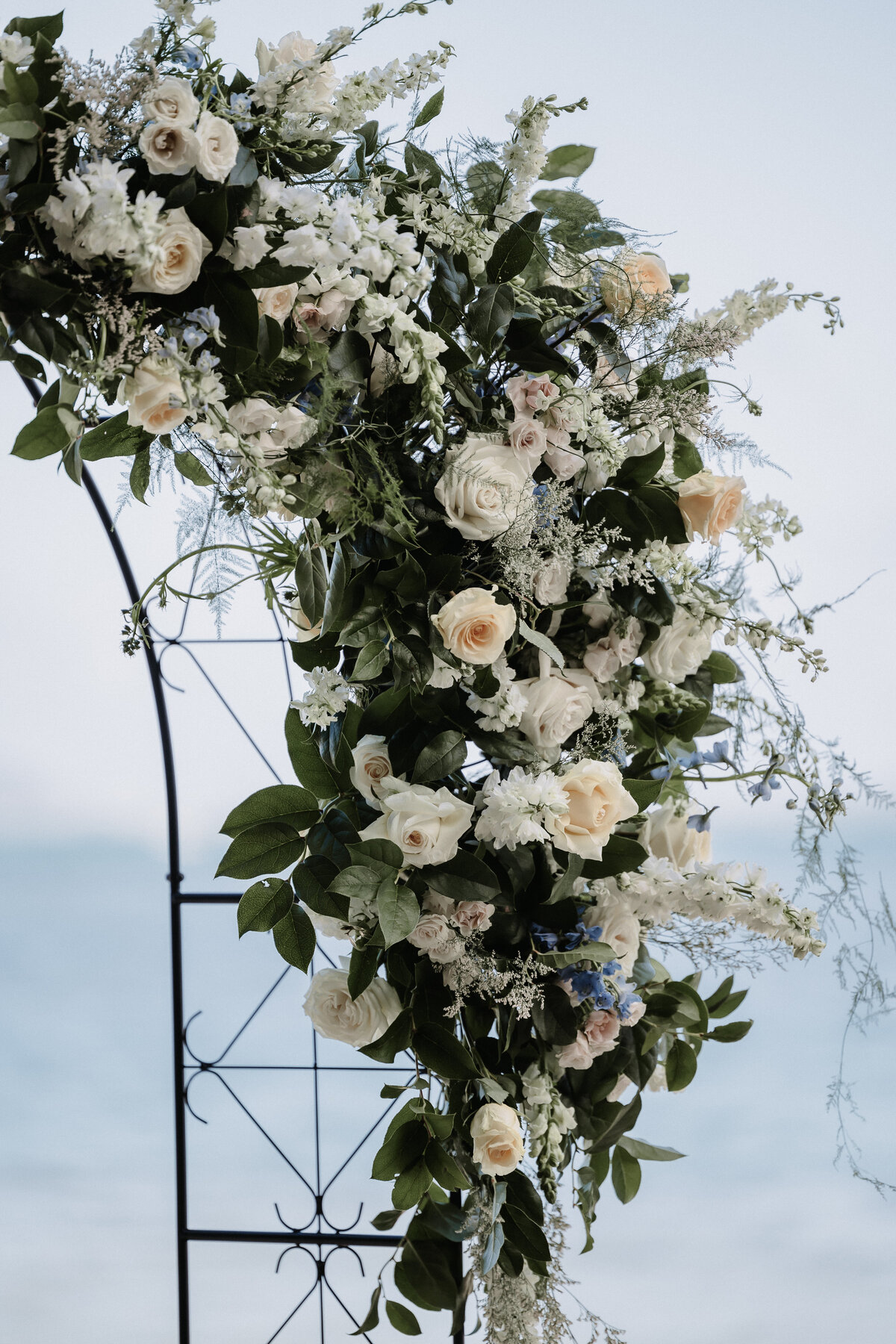 Wedding detail shot of ceremony arch florals that are yellow, ivory, green and blue