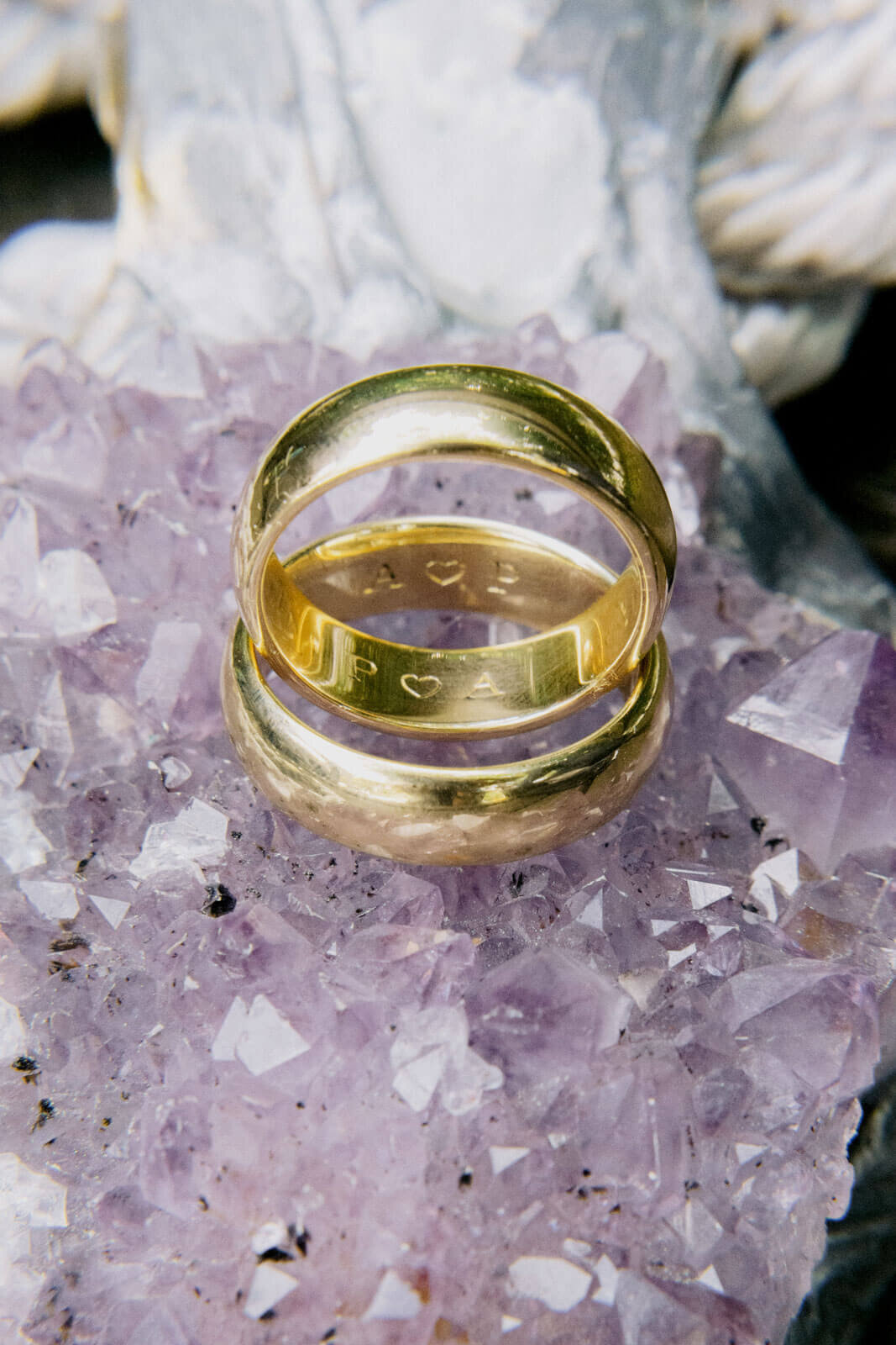 Two gold wedding rings are sitting on top of a purple precious stone. NYC City Hall Elopement Image by Jenny Fu Studio