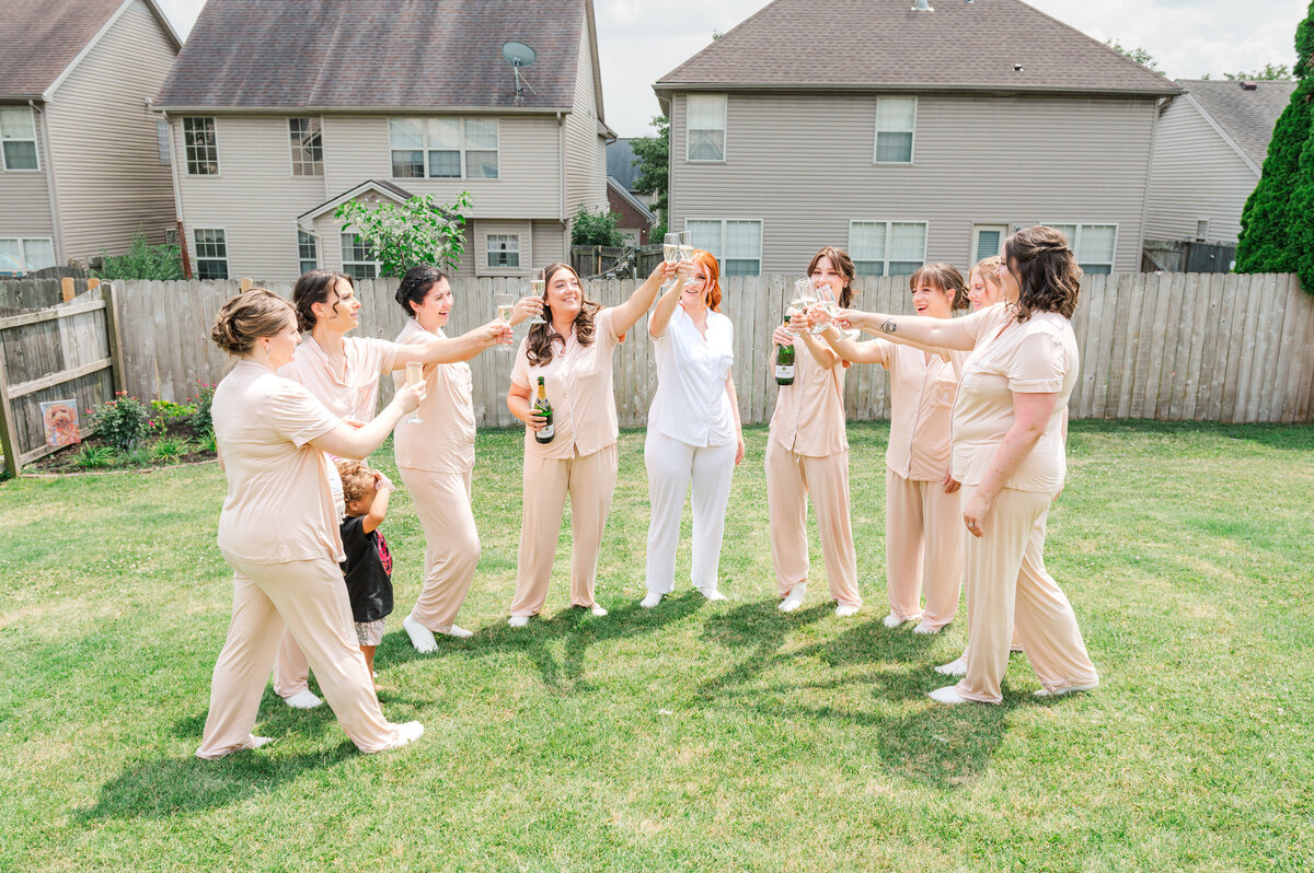 bride and bridesmaids pop champagne in pajamas on morning of the wedding