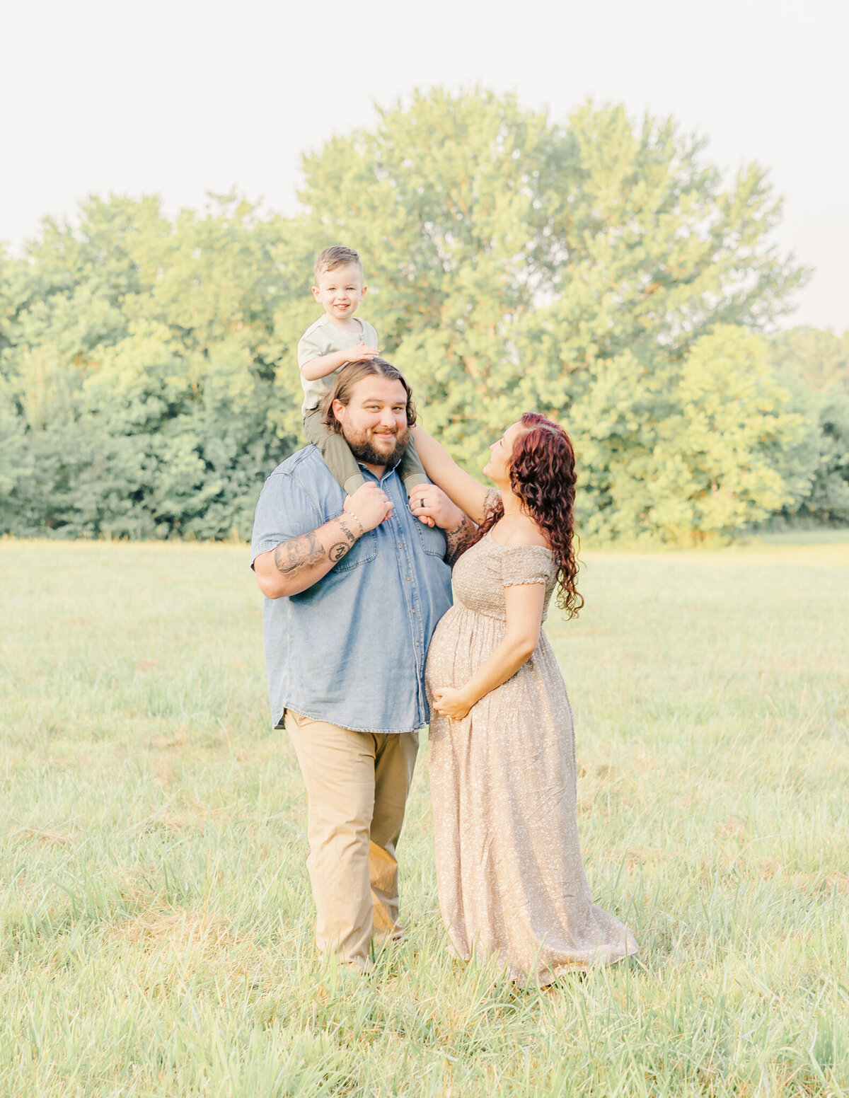 mother interacting with her toddler sitting on dad's shoulders during their summer photo shoot in the barfield community in rutherford county in murfreesboro