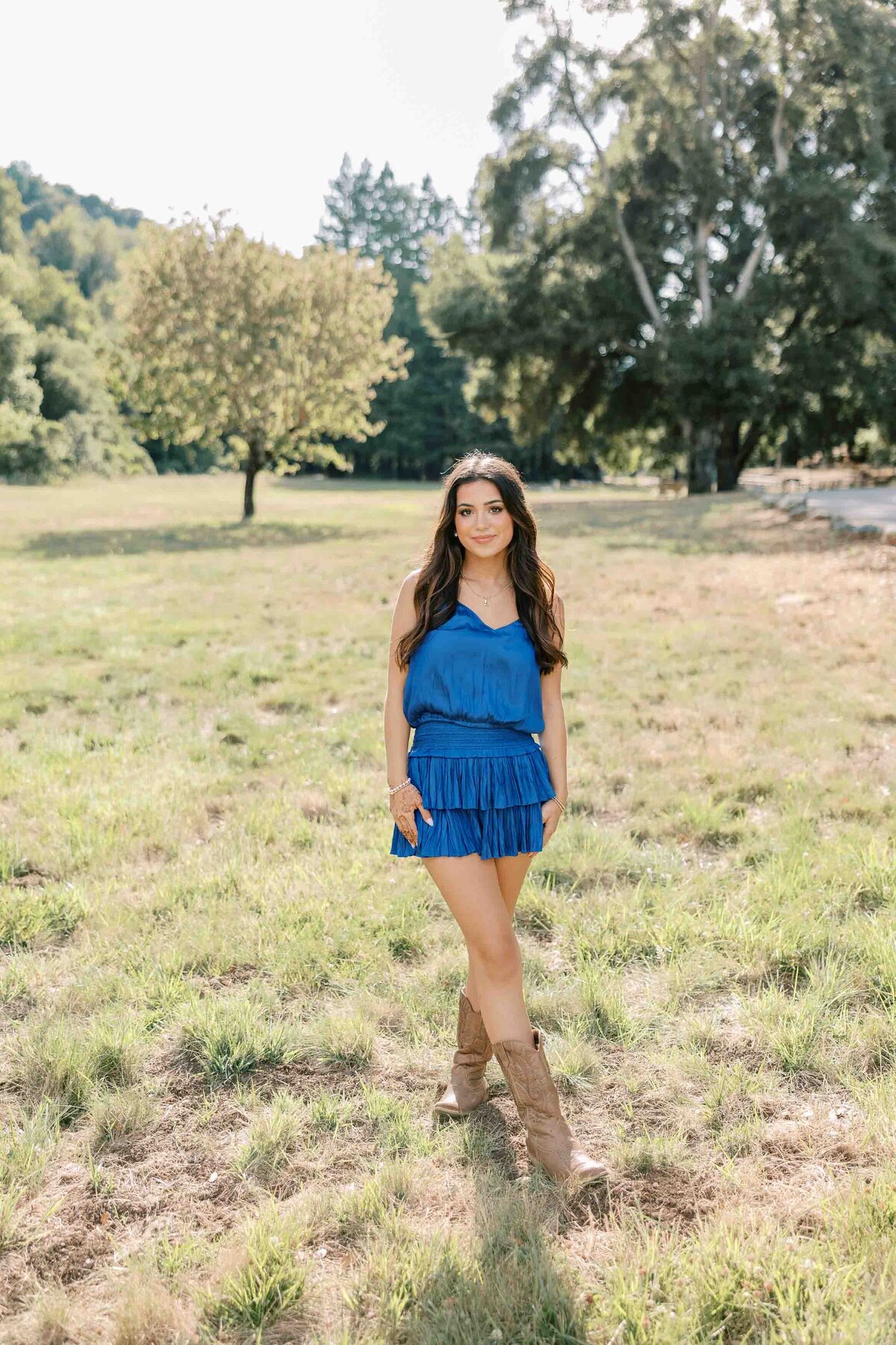 Brunette girl wearing a royal blue dress with her hands down by her side