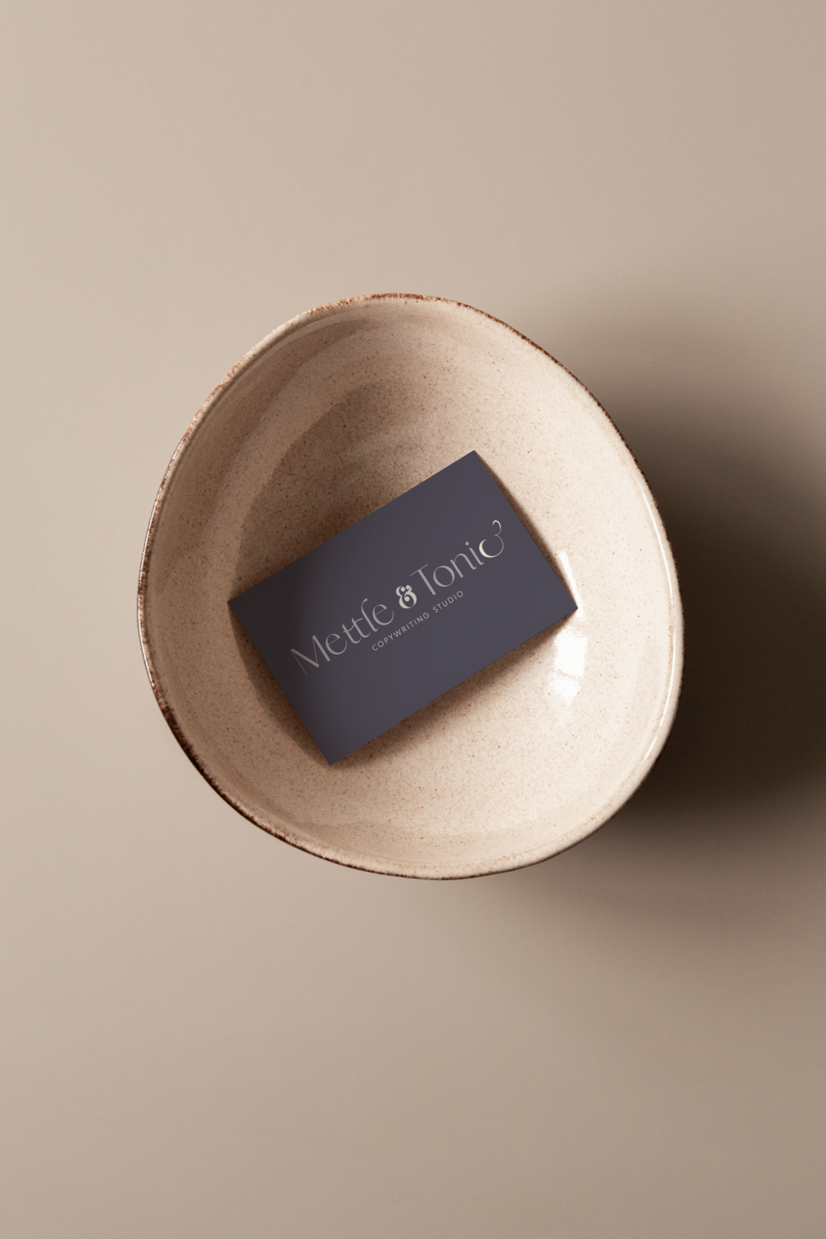 A business card  design for Mettle & Tonic copywriting studio placed inside a ceramic bowl