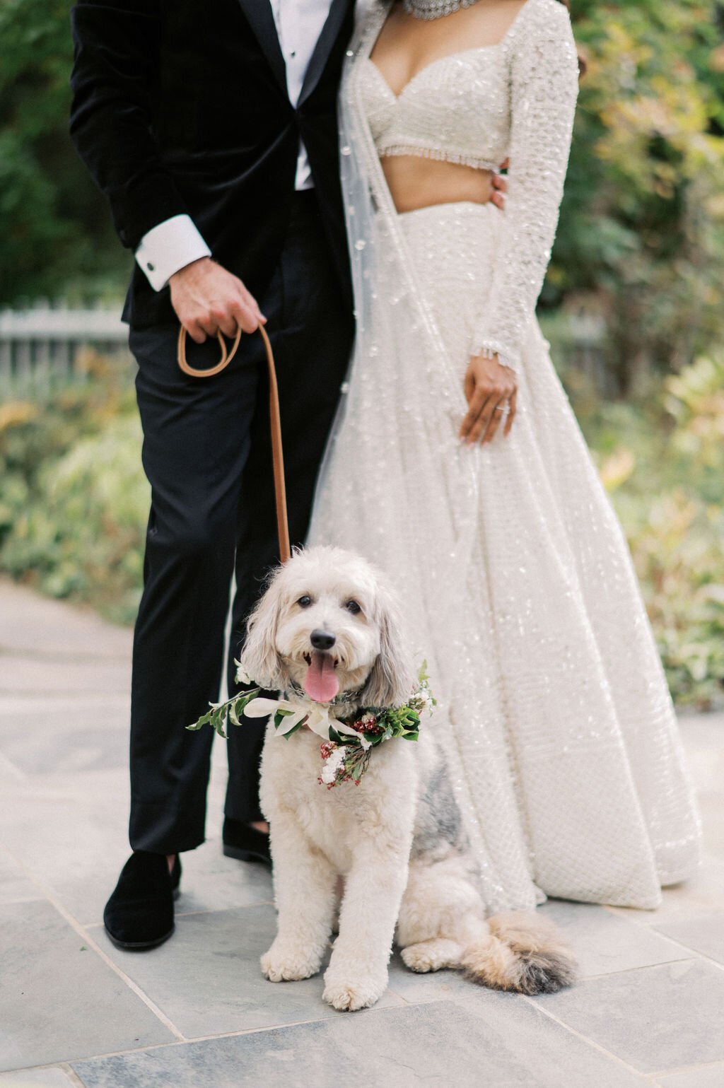Bride and groom standing with their dog wearing a floral collar during wedding portraits at Old Edwards Inn in Highlands, North Carolina.