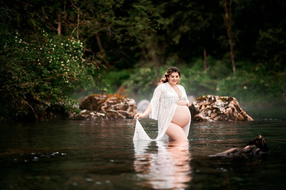 Expecting mother in a white lace cover in the river at Golden Ears Park, captured during an outdoor maternity session.