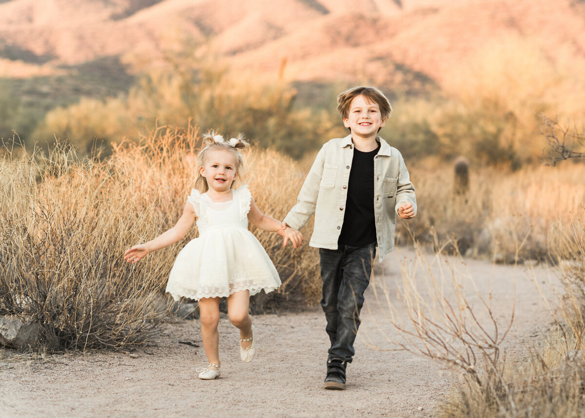 brother and sister running in the desert holding hands in north scottsdale az