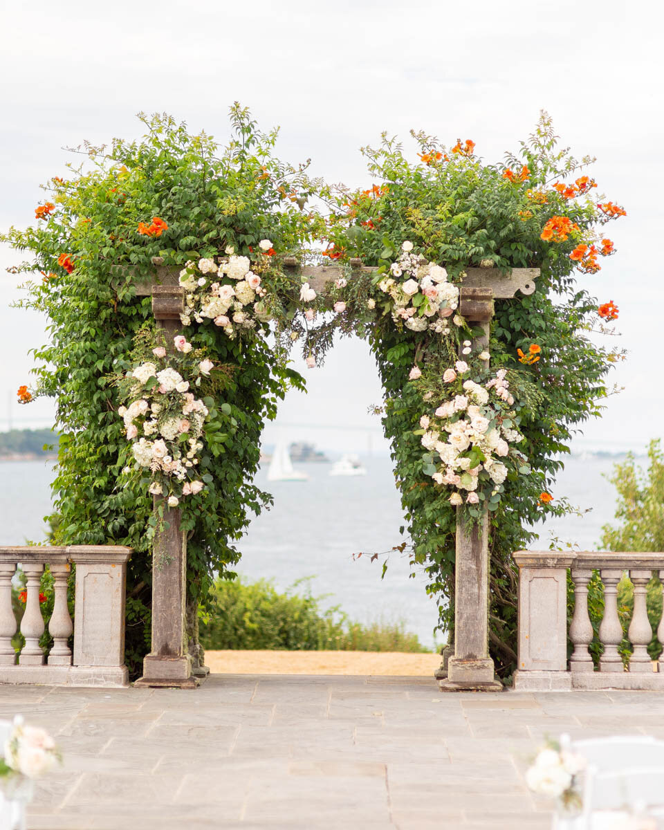 A rose and greenery ceremony arch at a wedding at Castle Hill Inn.