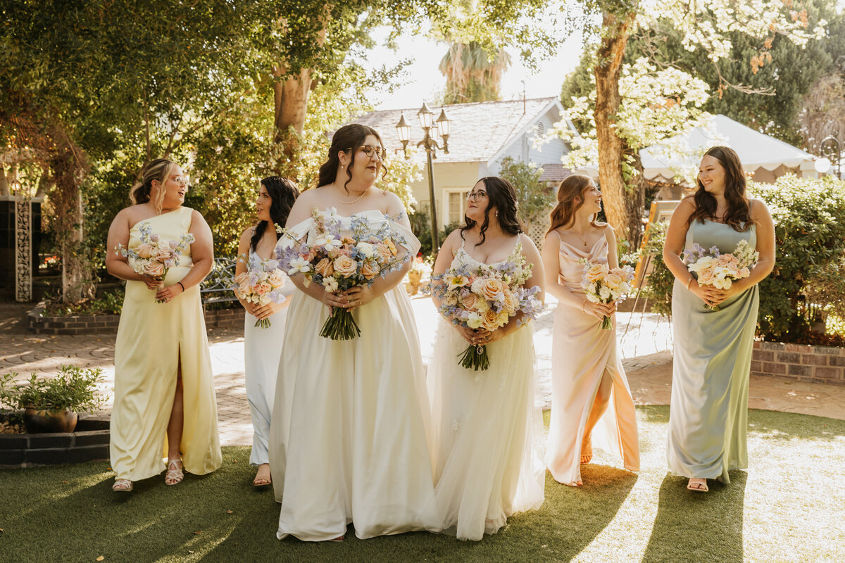 Newlyweds smiling with their wedding parties walking behind them 