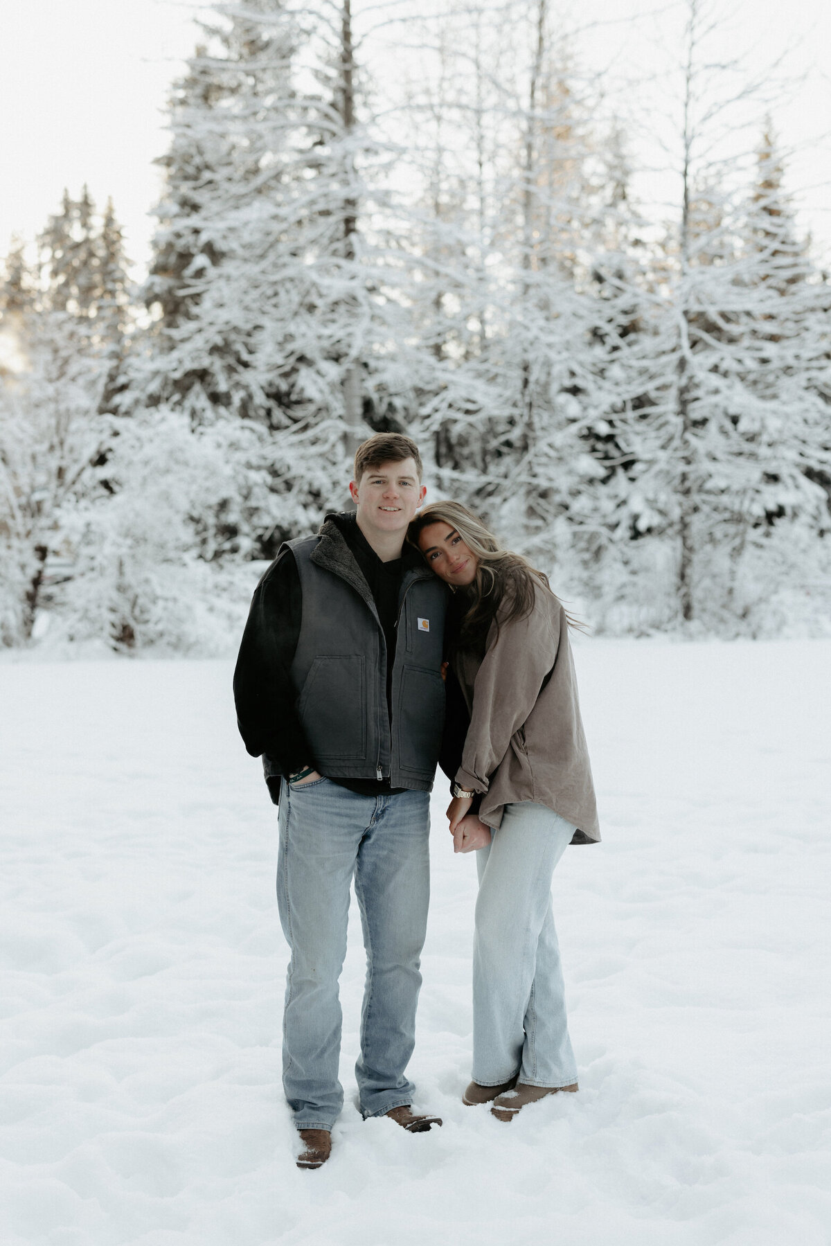 Woman wrapped on mans arm while standing in the snow.