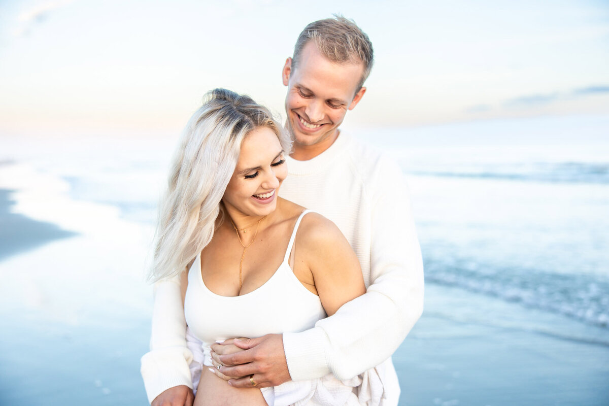 Expecting parents embracing on the beach