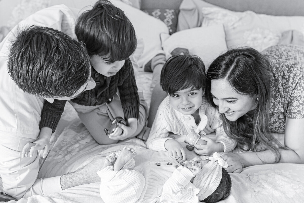 A joyful family welcomes their newborn with love – captured by a Birmingham newborn photographer. Big brothers excitedly gather around their baby sister, as mom and dad share a moment of warmth and connection during this lifestyle newborn session at home.