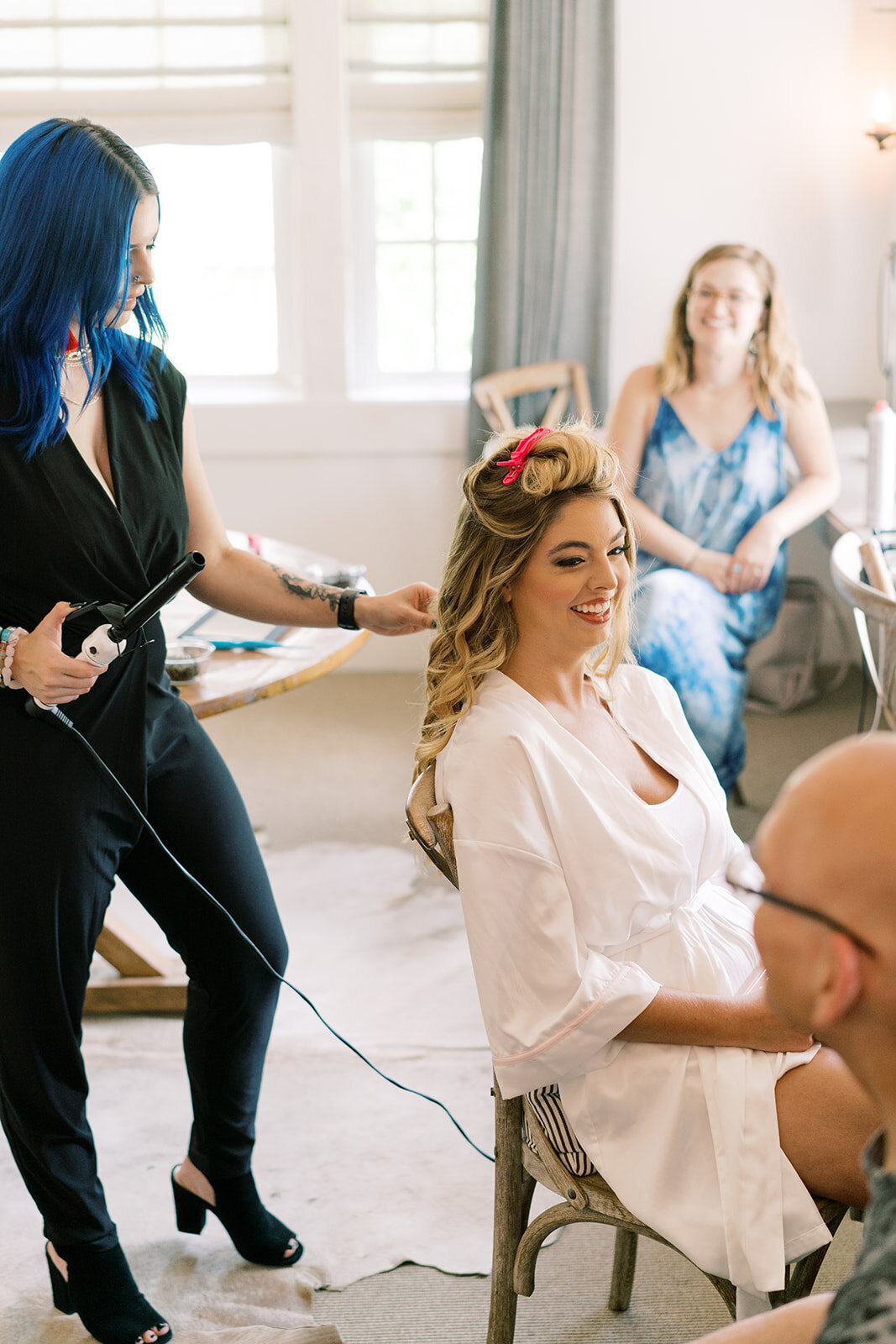 bride smiling while hairstylist curls her hair