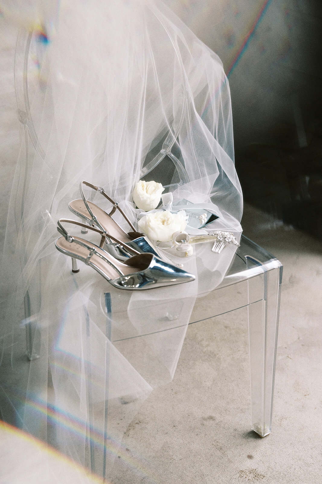 A clear chair with a veil and high heel shoes.