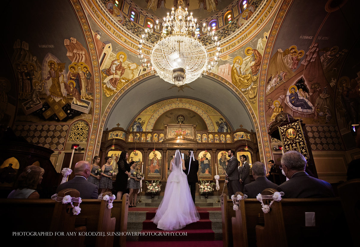 charlotte wedding photographer Jamie Lucido captures a moment during the ceremony with bride and groom at the altar at Holy Trinity Greek Orthodox Church in Charlotte, NC