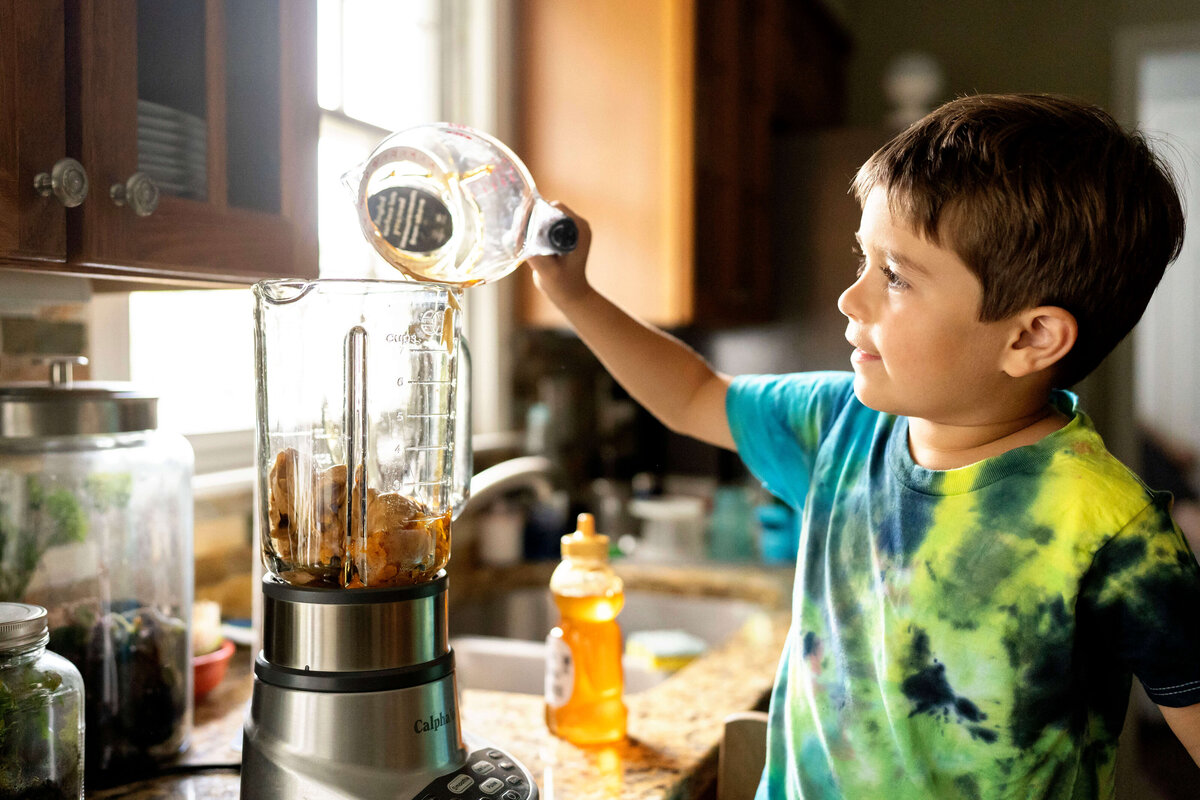 Young boy pouring food into blender