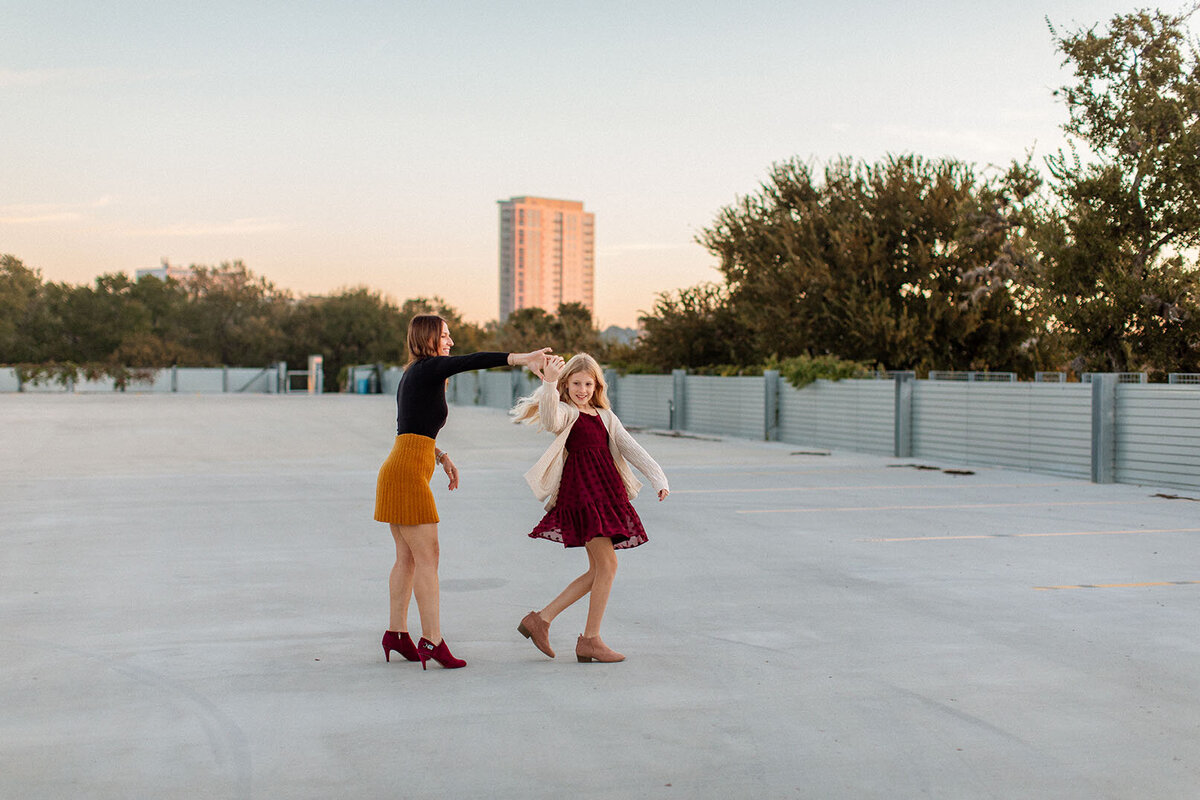 Two girls twirling in their dresses outdoors in San Antonio, photographed by Sara James, a family photographer.