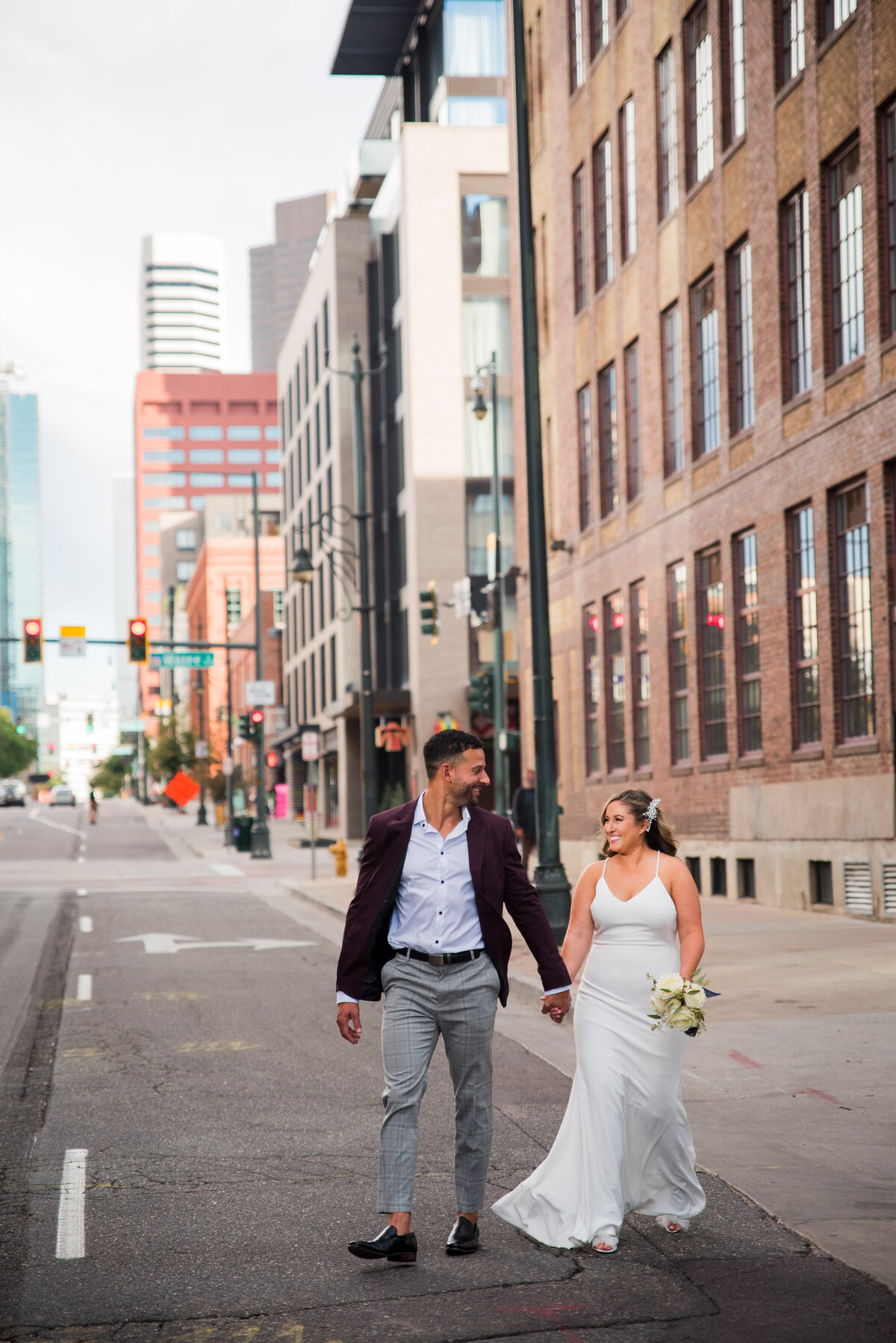 A bride and groom walk hand in hand through the streets of downtown Denver, captured by Colorado photographer, Two One Photography.