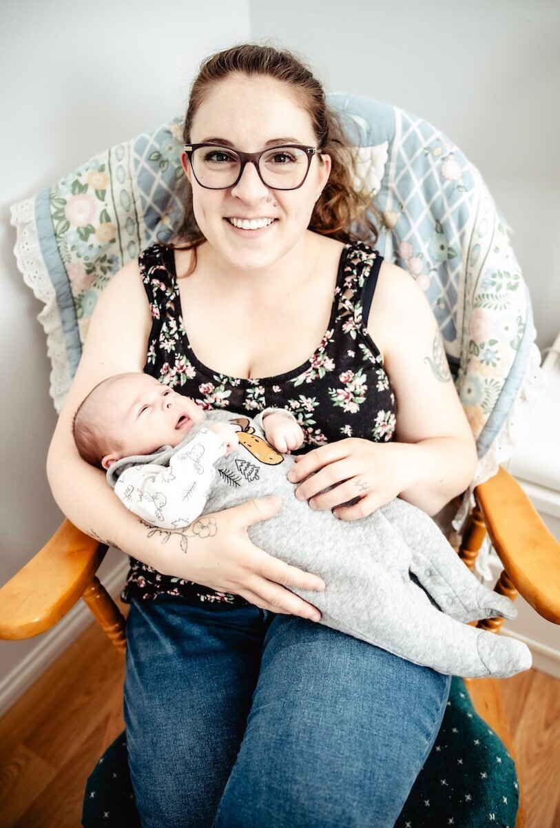 A new mom holds her two day old baby in her lap in her Edmonton home