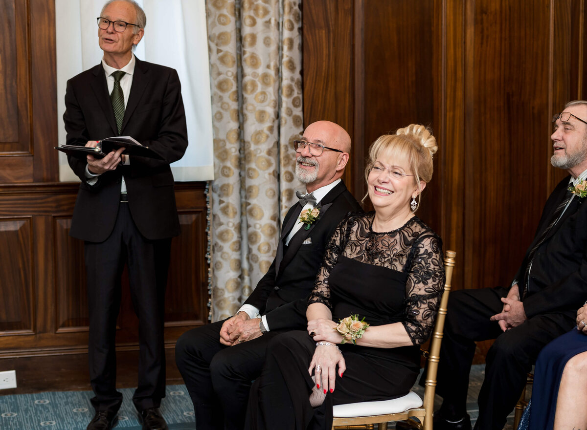 a photo of the parents of the groom smiling and laughing as they watch their son get married during his Ottawa wedding ceremony at the Chateau Laurier hotel