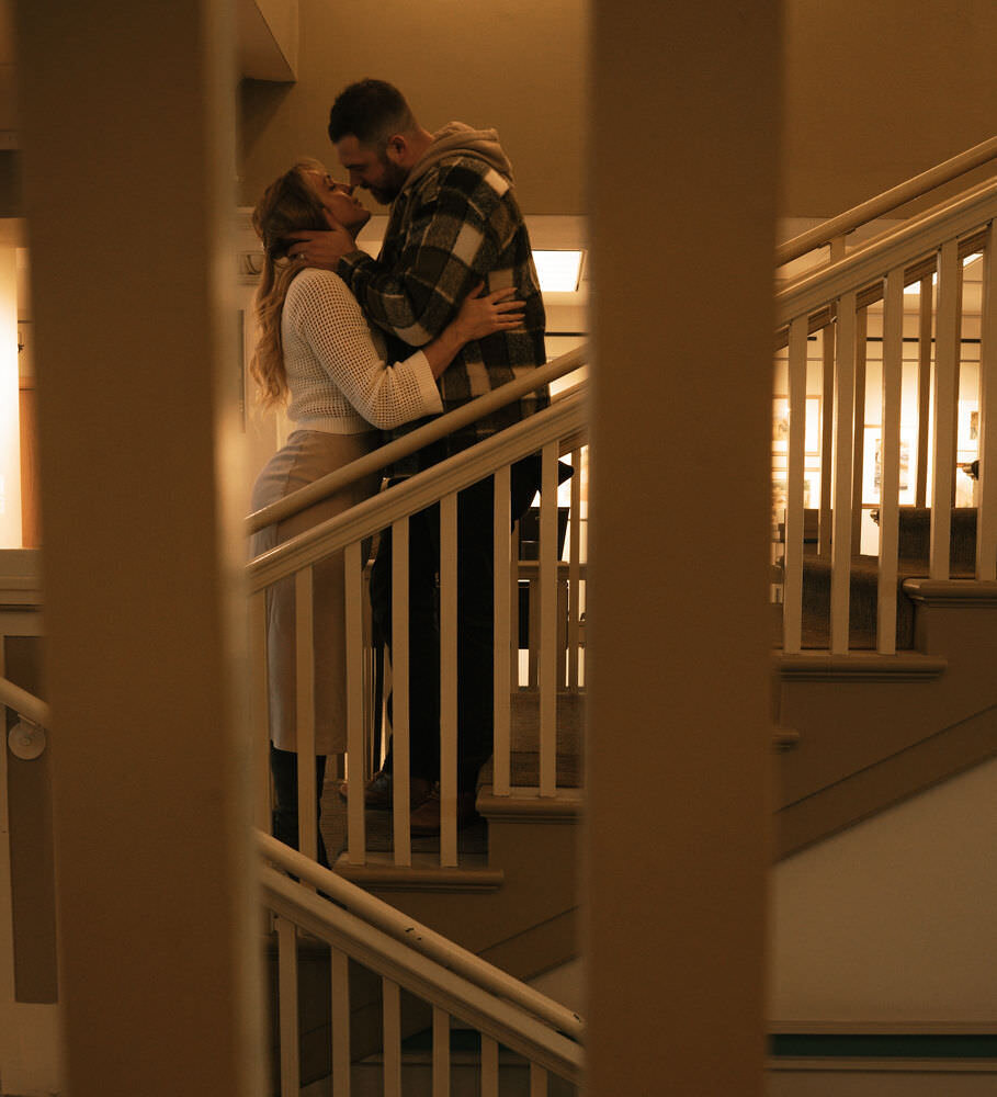 A book-loving couple shares a romantic moment among the bookshelves during a library engagement session in Spokane, Washington.