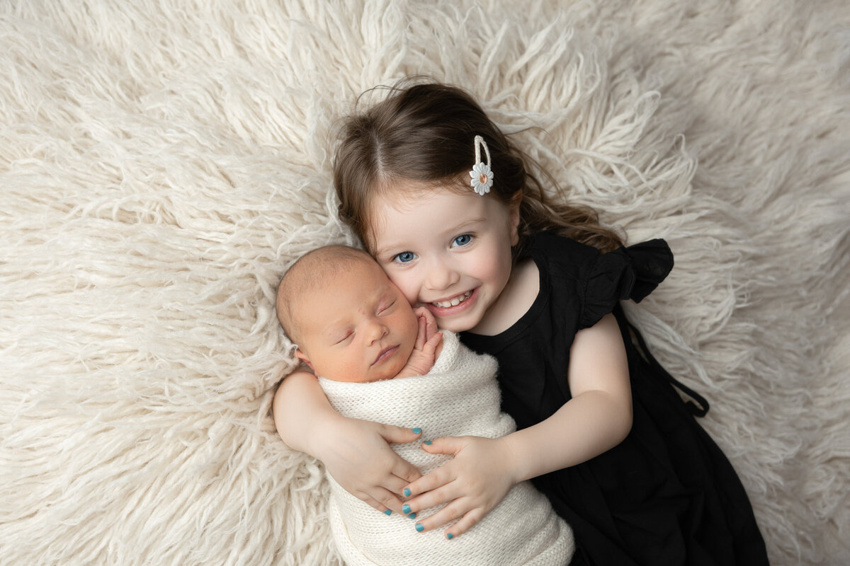 newborn and sister studio flokati pose