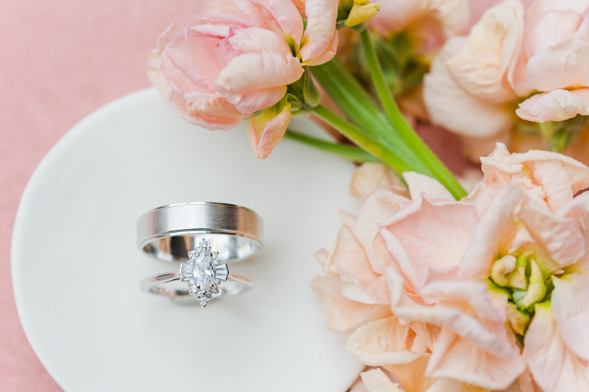 white-gold-wedding-bands-on-an-ivory-ceramic-dish-with-pink-snapdragons