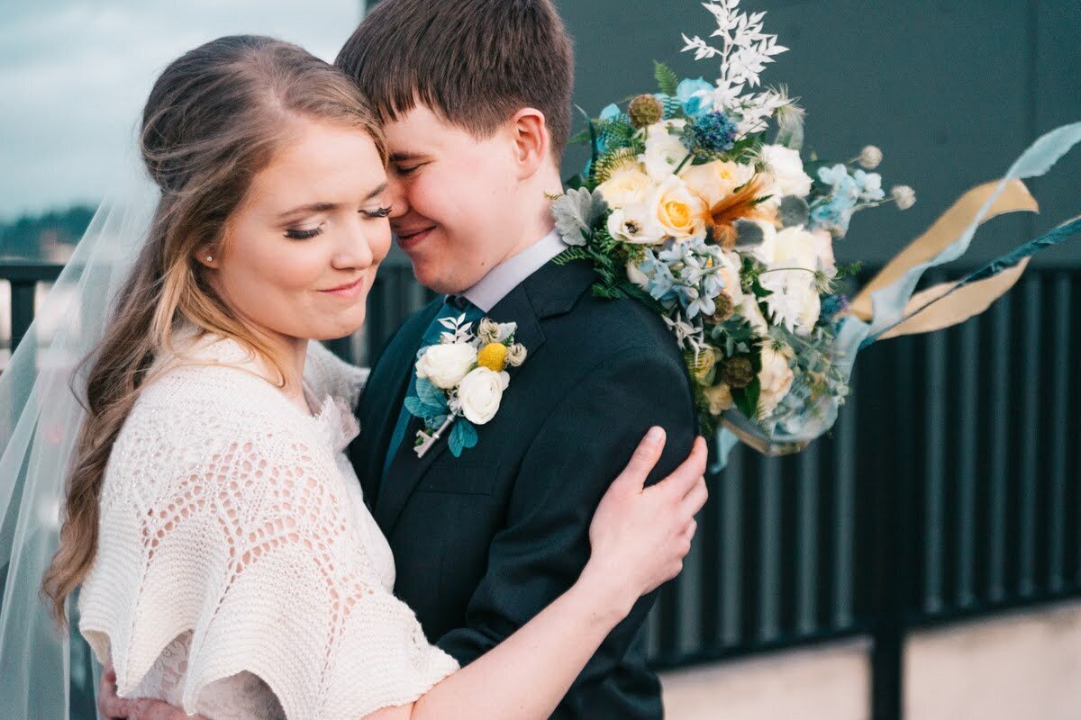 Bride and groom embrace and she is holding her bridal bouquet.