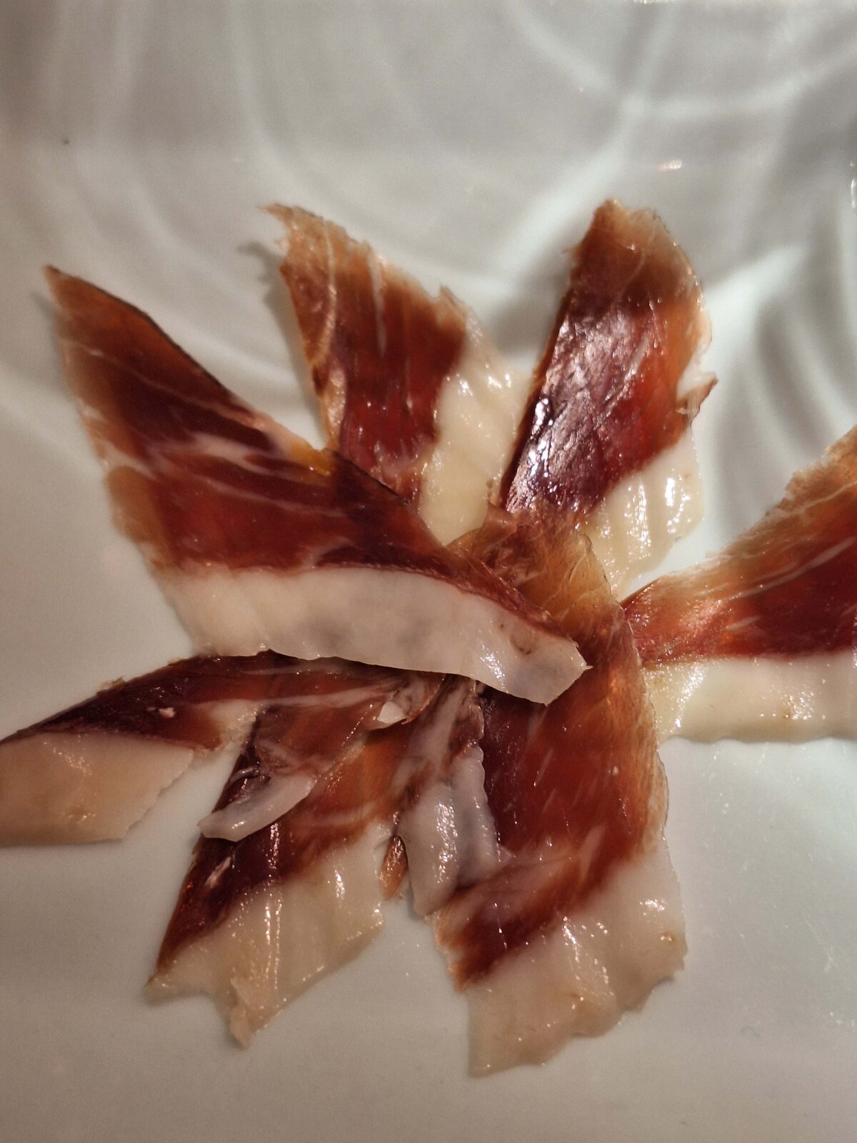 Premium Spanish ham on a plate served at Maria Cristina Barrero's Gourmet Wine Experience at Coalla wine bar.