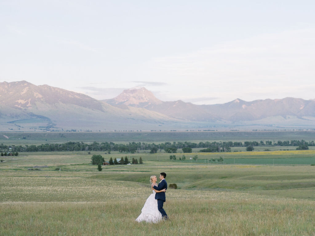 bride and groom embracing with the Montana mountains in the background