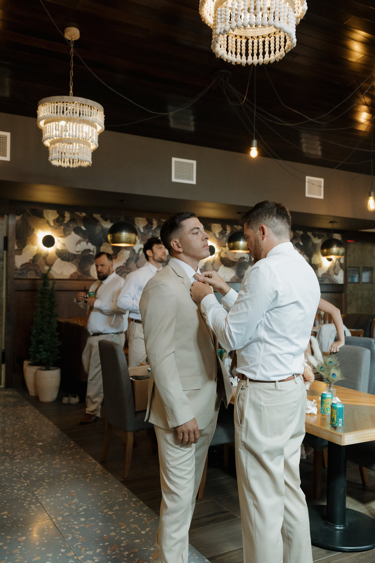 A groom getting ready and getting his tie tied,  at Lucky Arrow Retreat.