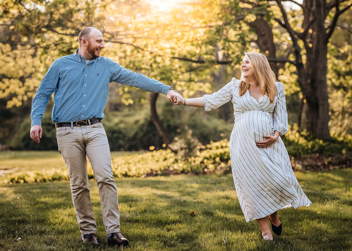 Pregnant woman and husband holding hands and walking in field in P