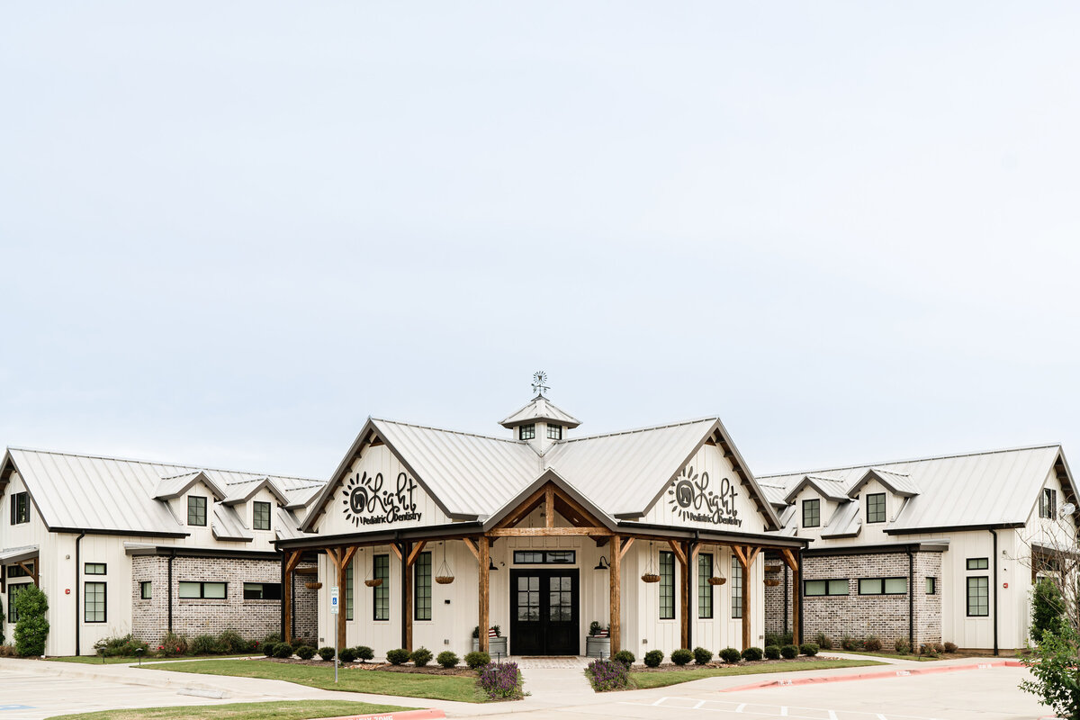 white board and batten building with brick accents and metal gable roof