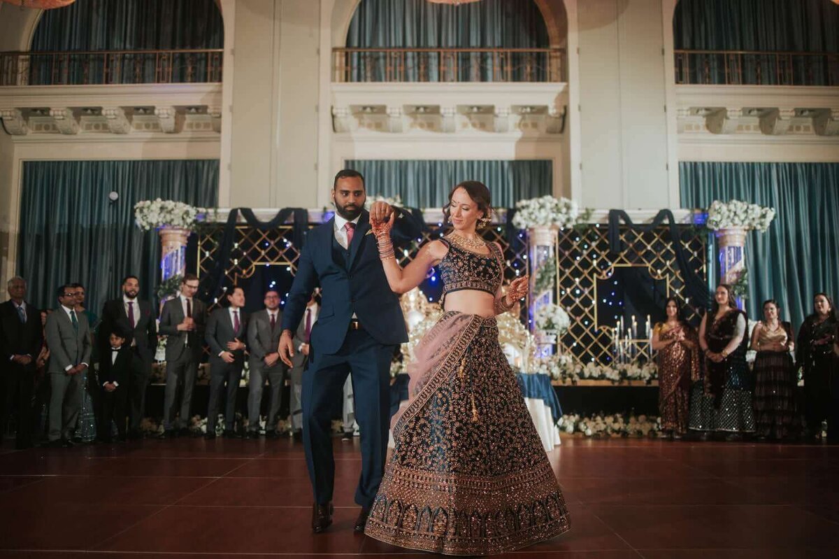 The groom twirls his bride during their first dance surrounded by their dear friends and close ones.