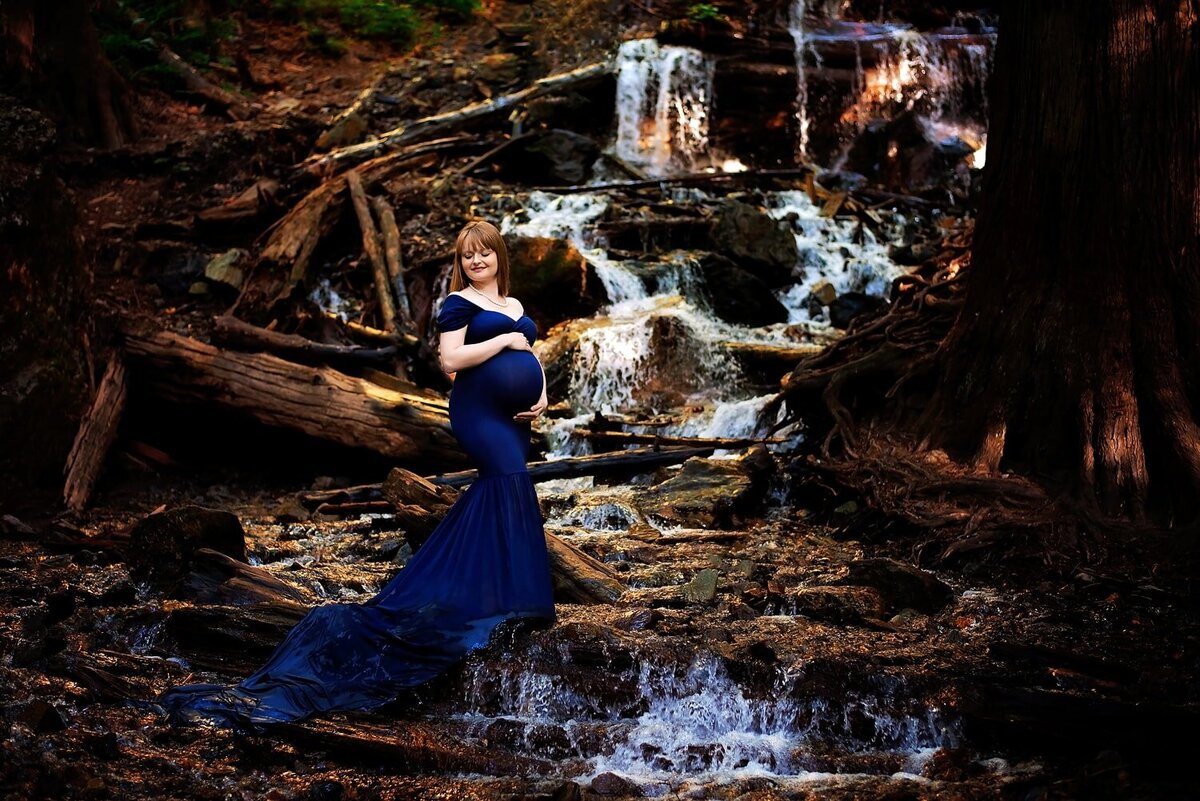 Epic maternity photoshoot at Bridal Falls waterfall with mom-to-be in royal blue Chicaboo Monroe gown