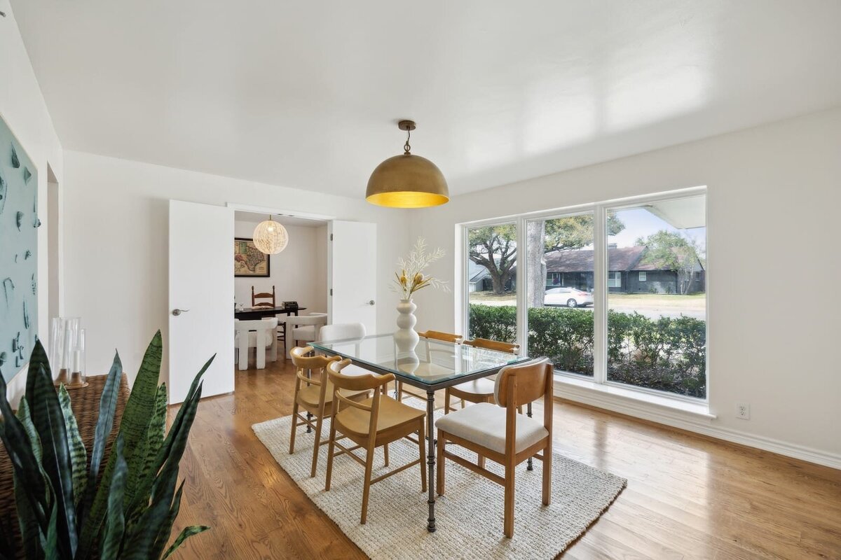 Bright dining room at 3120 Chapel Downs Dr Dallas TX featuring floor-to-ceiling windows, midcentury modern lighting, and natural hardwood floors — listed by Haven Realty Group.