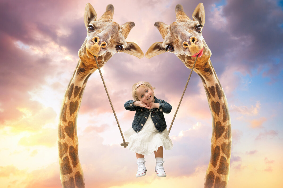 Milestone portrait of a young girl swinging between giraffes at sunset. A playful, imaginative scene for storytelling sessions.