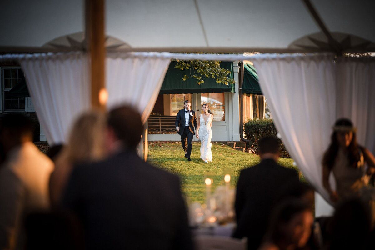 A couple enters their tent reception at a destination wedding in Vermont