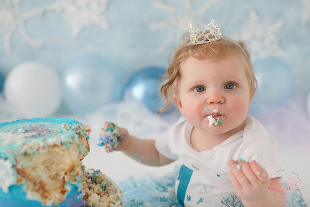 baby girl eating her first birthday cake