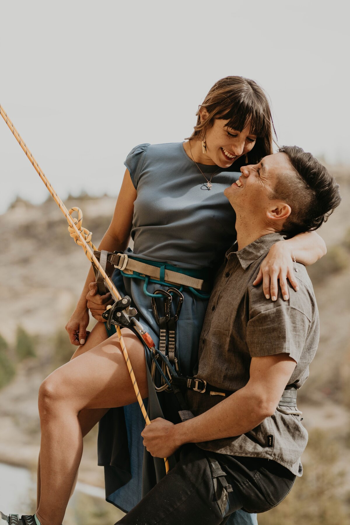 Couple holding each other while rock climbing at engagement photos at Smith Rock