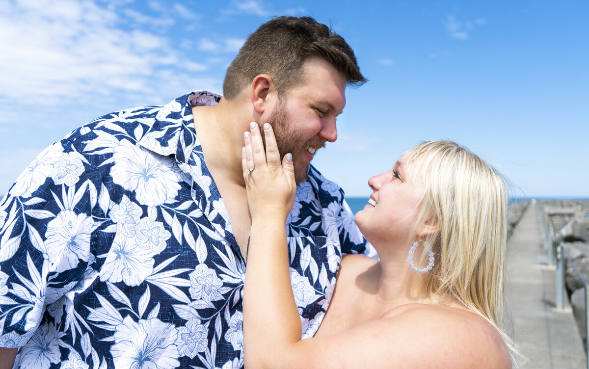 Photo of a woman holding her fiance under a bright blue sky