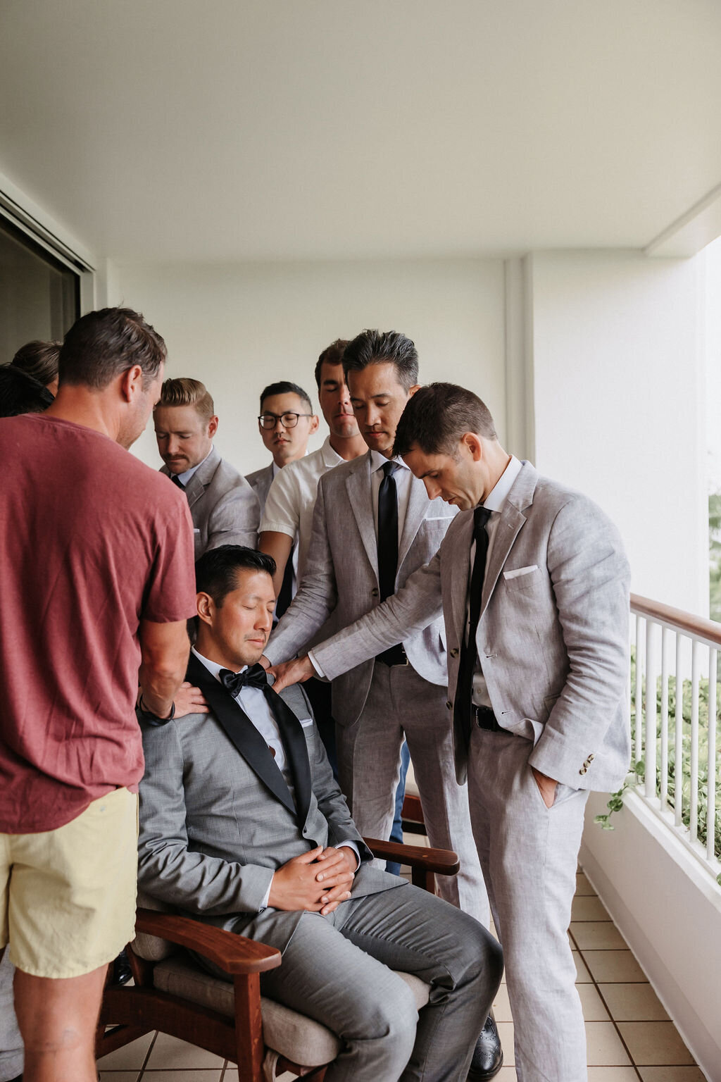 groom being prayed over by groomsman morning of his wedding at four seasons oahu