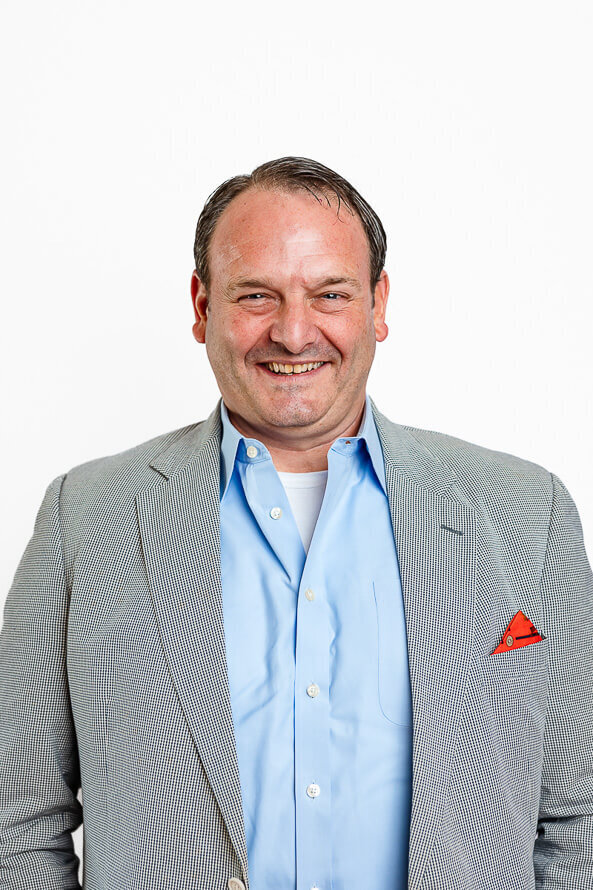 Man smiles largely on a white backdrop.