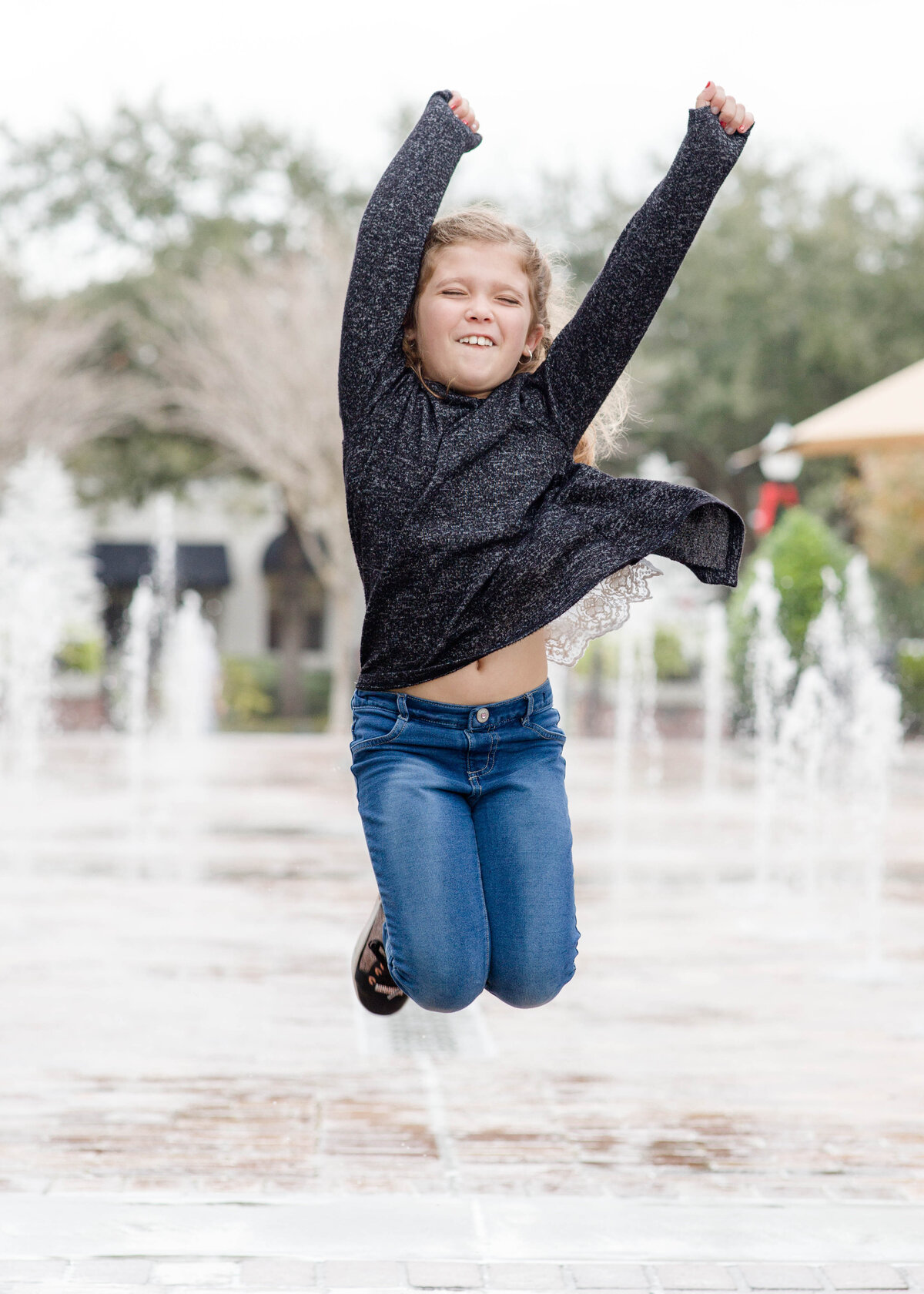 little girl jumping at splash padby Lucas Mason Photography in Orlando, Windermere, Winder Garden area