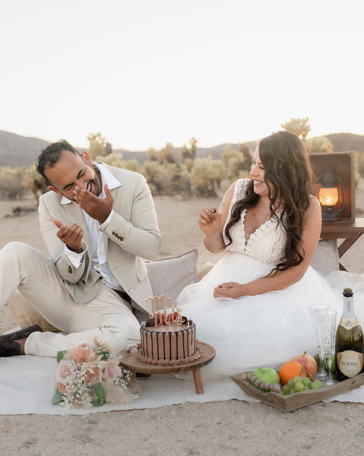 Joshua Tree elopement with bride and groom at Cholla Cactus Garden laughing and being silly during picnic and cake cutting. 