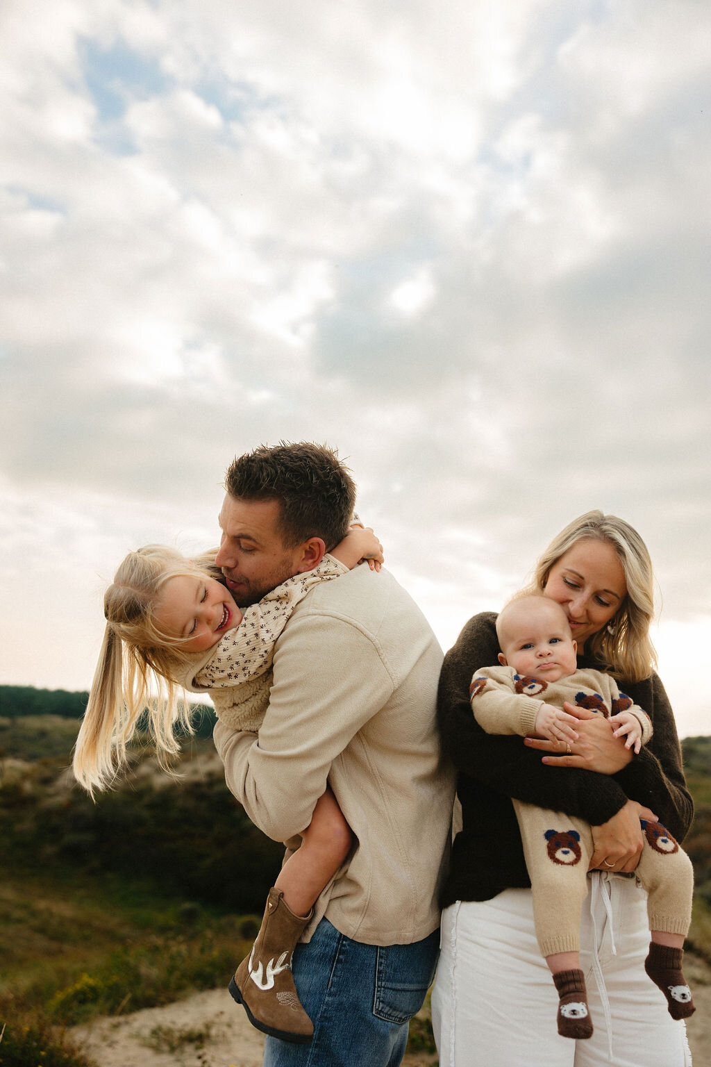 Gezinsfotoshoot in de duinen van Wassenaar met ouders en twee jonge kinderen in warm, natuurlijk licht door Linda Photography