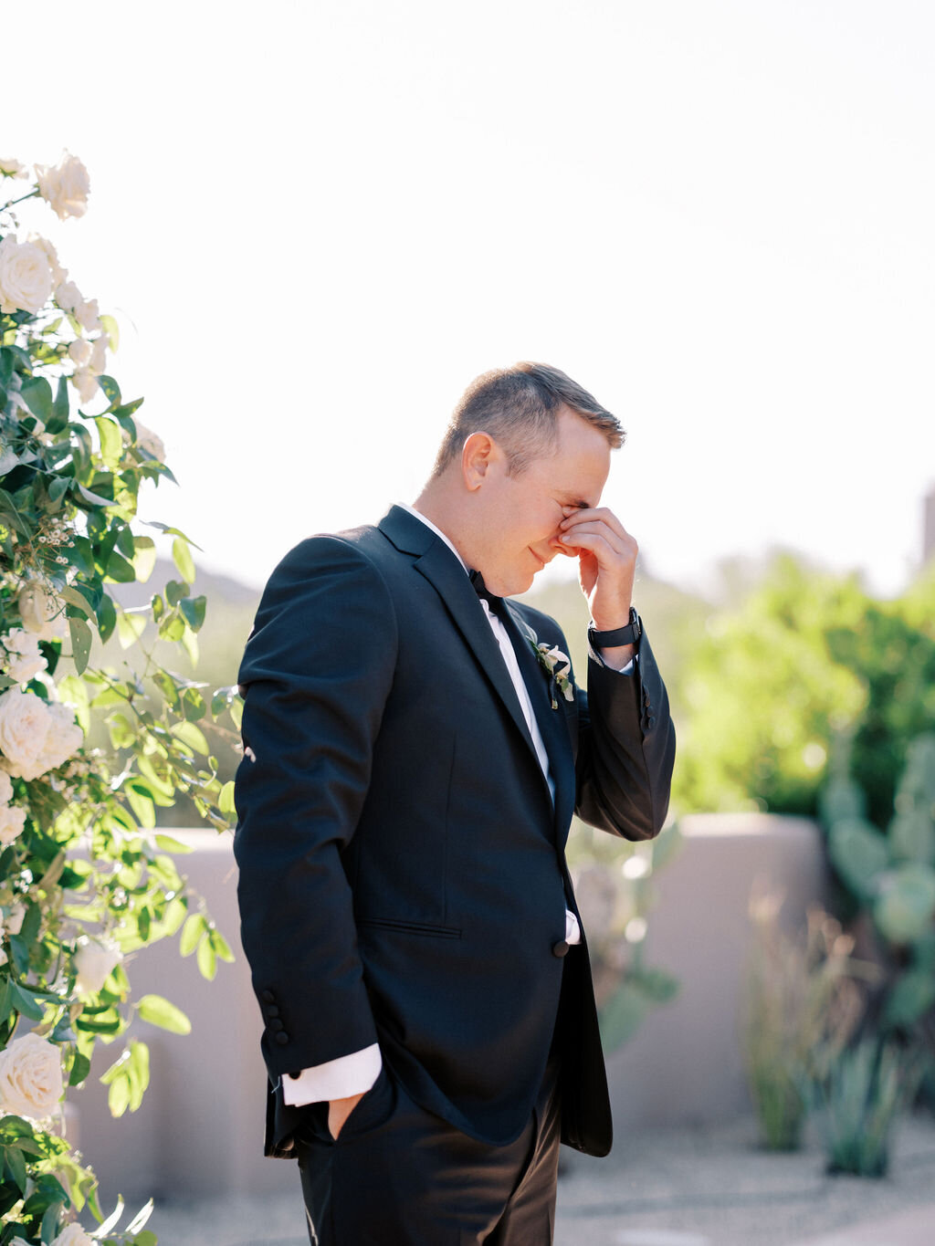 A touching moment as the groom wipes away tears of joy while watching his bride walk down the aisle during their heartfelt wedding ceremony.