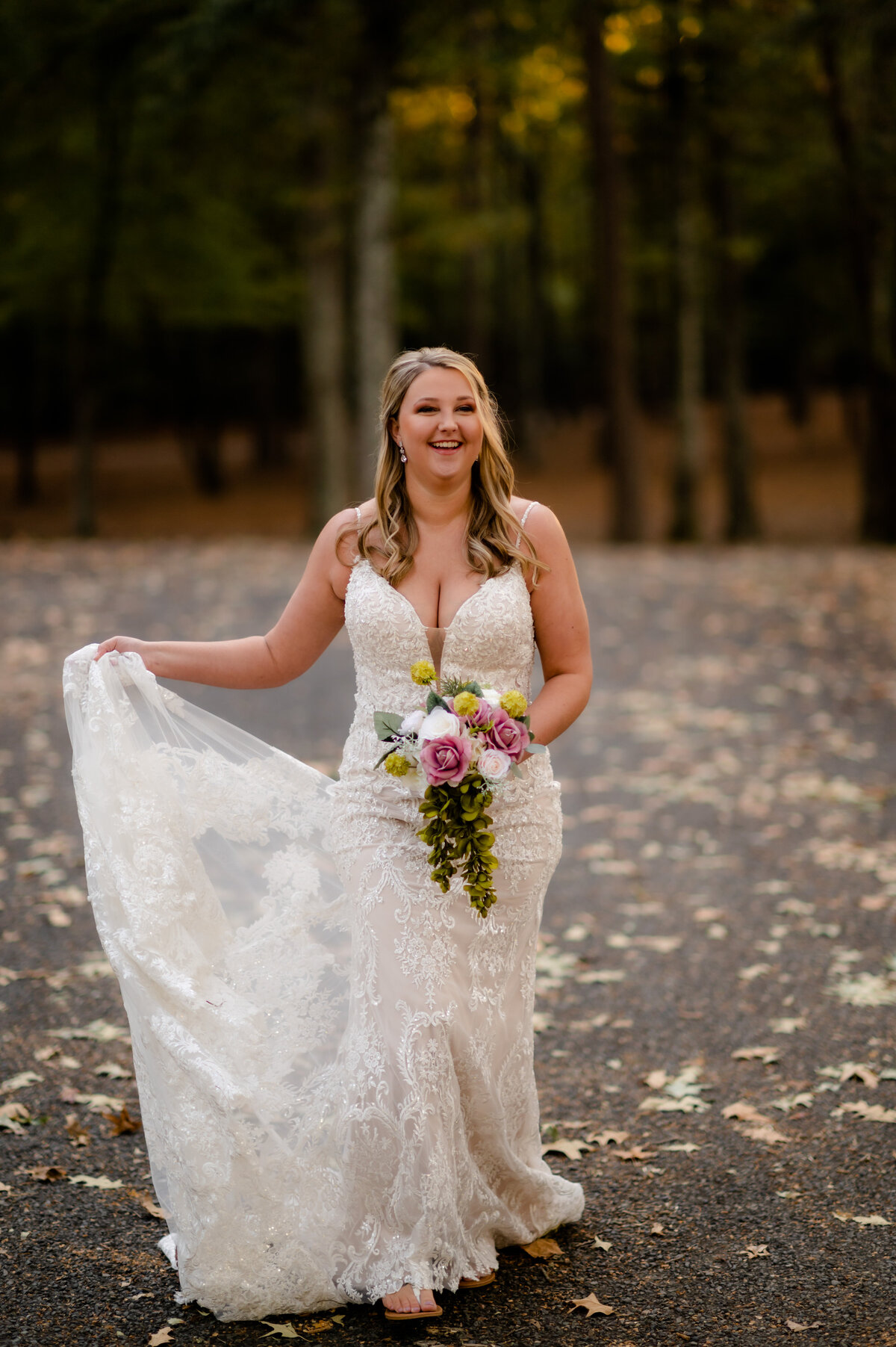 bride dancing in her wedding dress with fallen leaves surrounding her as she smiles