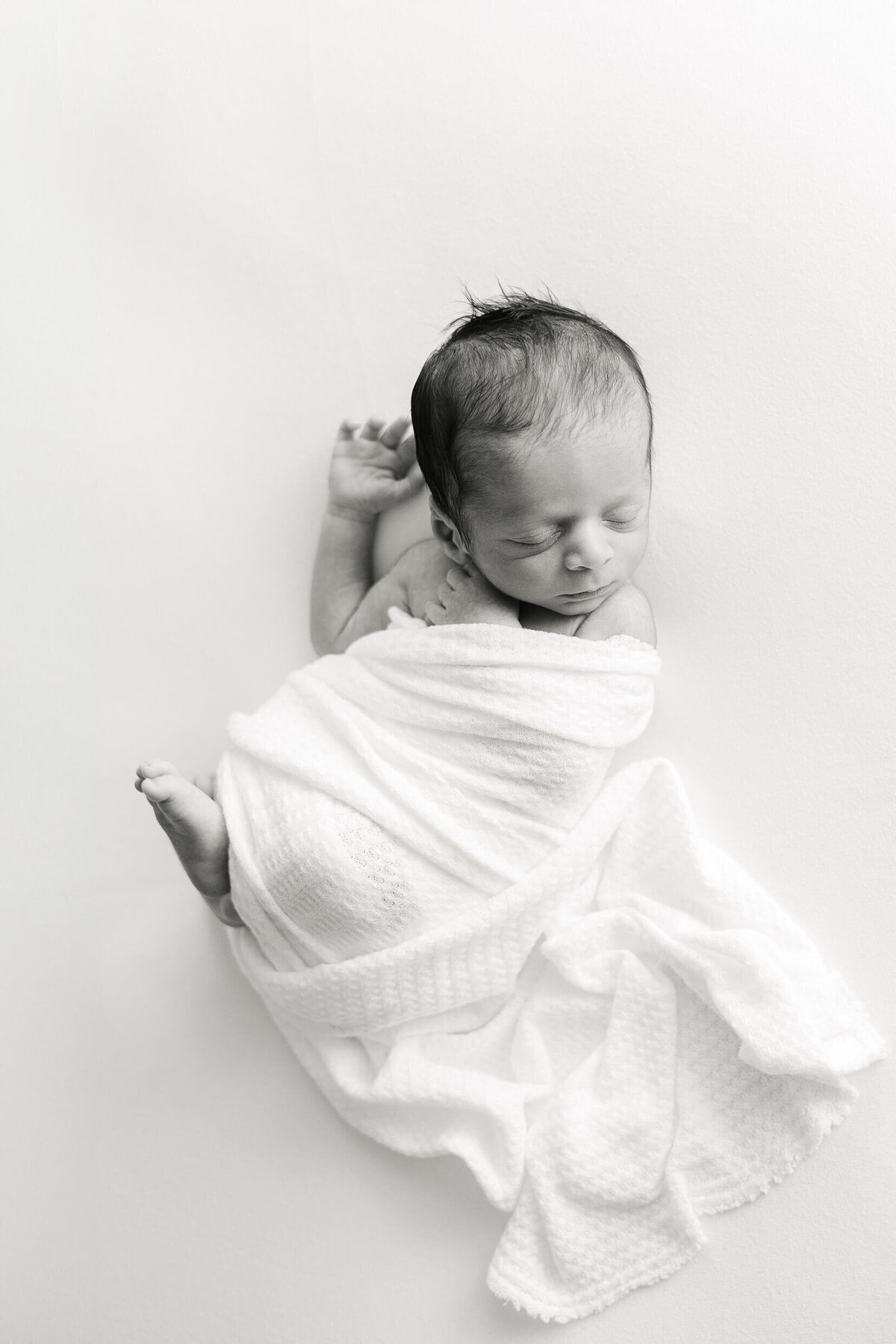 a newborn baby stretching out his arm while he sleeps
