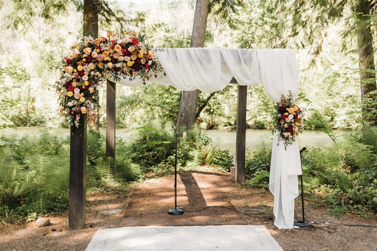 Floral installation along an arbor at an outdoor wedding ceremony.