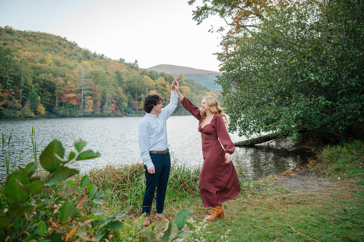 Man twirls his fiance around in front of the beautiful lake at Vogel State Park. Photo by Amanda Touchstone, a North Georgia engagement photographer